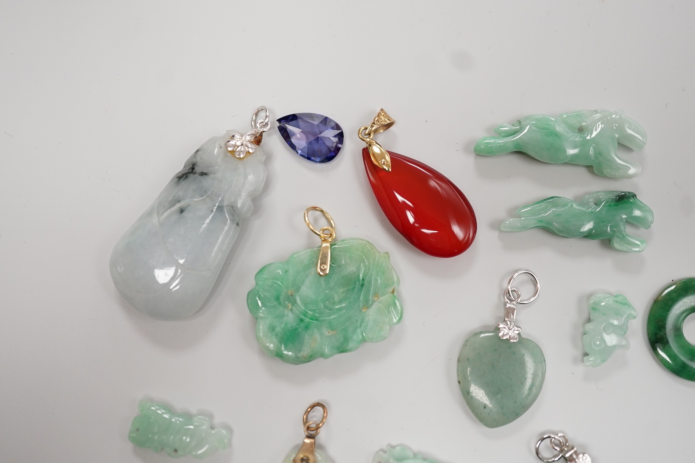 Twelve assorted carved jadeite items including five pendants, largest 40mm, a 14k mounted carnelian pendant and an unmounted pear cut simulated Tanzanite.